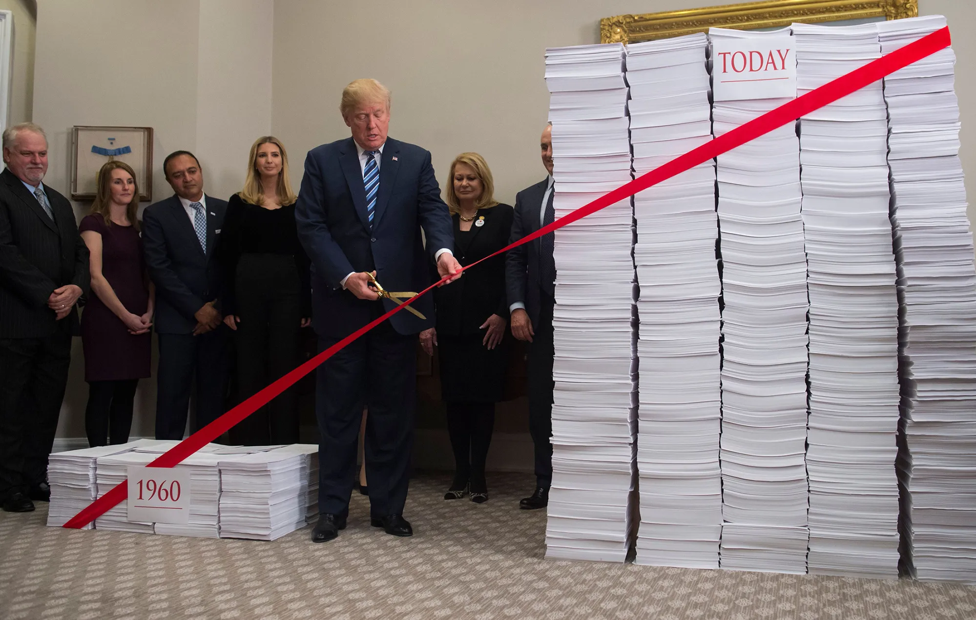 Trump cuts a red tape tied between two stacks of papers representing the government regulations of the 1960s and the regulations of today&nbsp;in Washington, D.C. on Dec. 14, 2017.