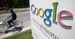 A Google employee rides by the company's main campus in Mountain View, California, a prototypical suburban tech campus.