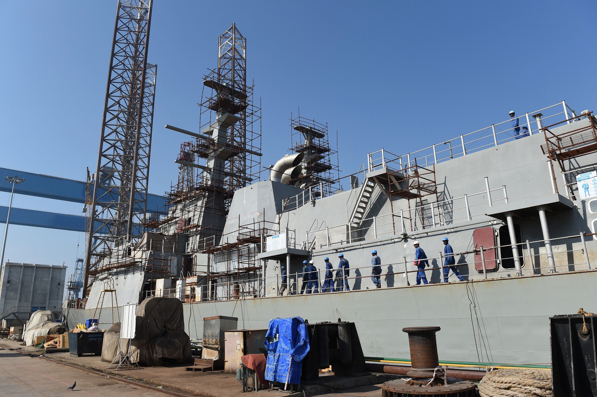 Reliance Naval and Engineering Ltd. &nbsp;workers walk on the deck of a ship at the RNEL shipyard at Pipavav.