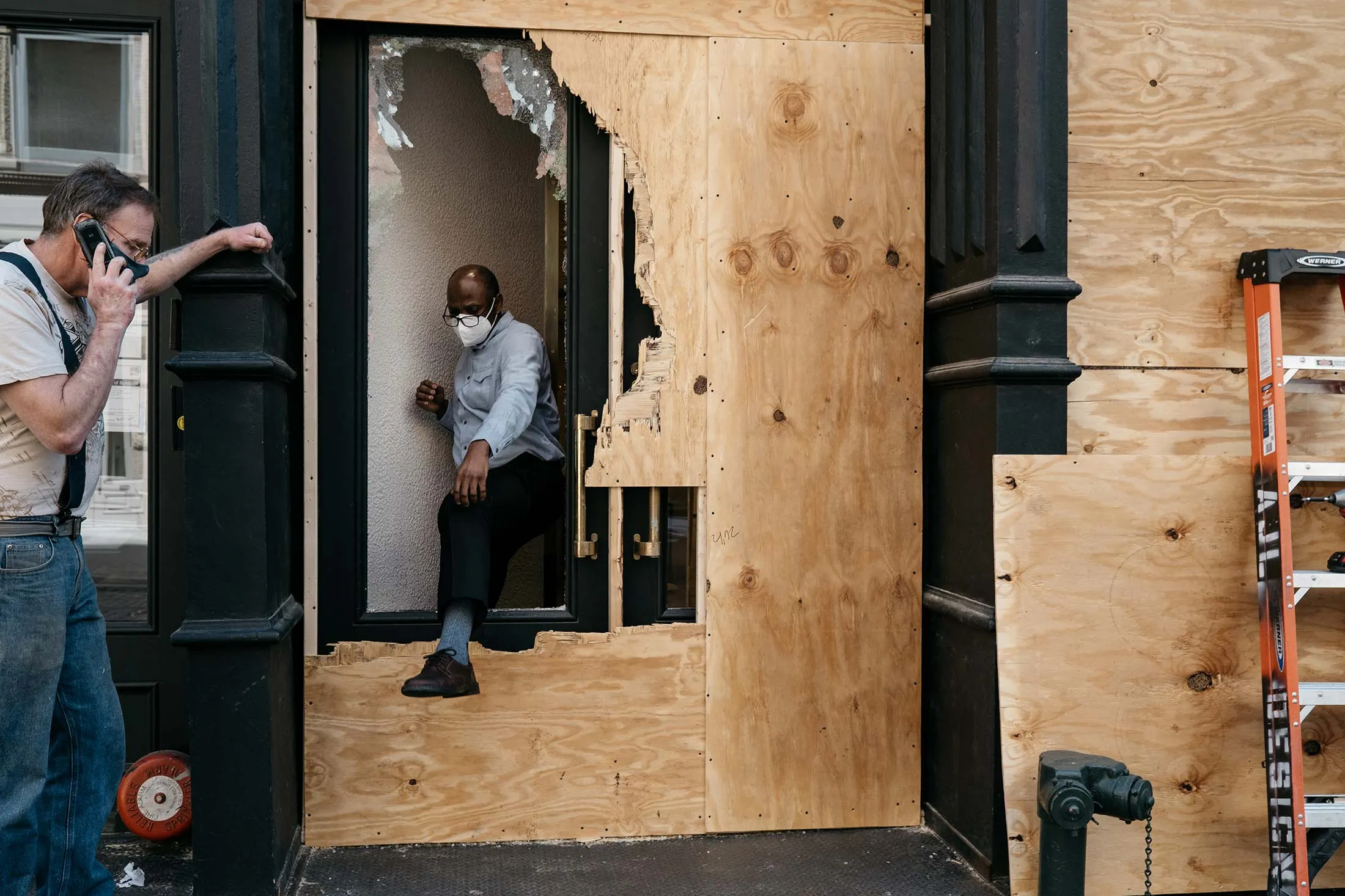A man steps through a broken storefront window&nbsp;in lower Manhattan on June 1.