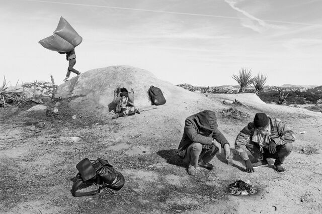 Asylum seekers from China sit in a desert with a campfire while waiting for US Customs and Border Protection agents to process them after arriving near Boulevard, California, on Nov. 26, 2023. 
