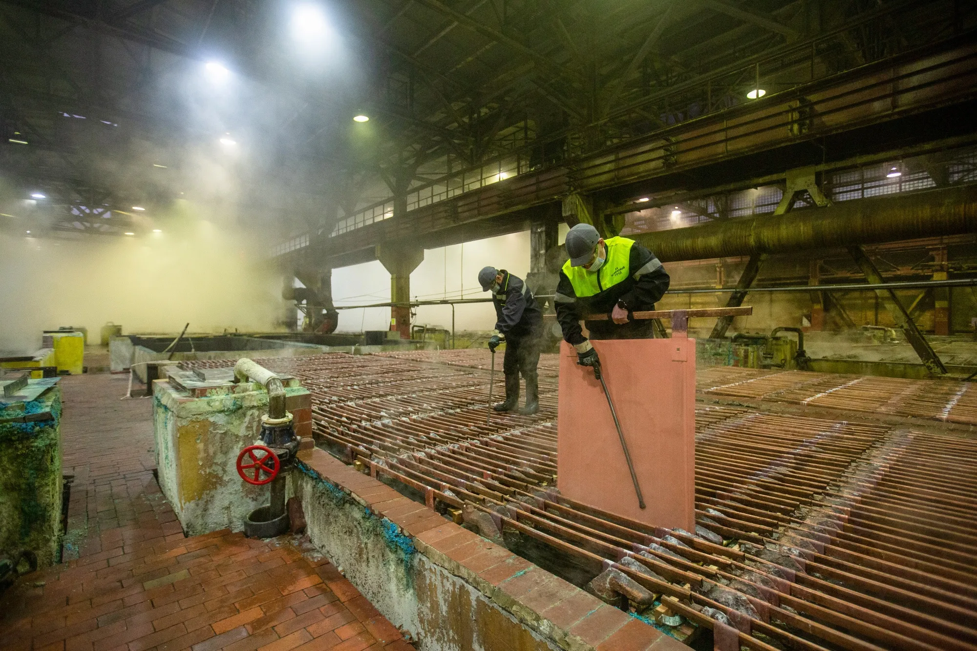 Workers check copper cathode and anode sheets in an electrolytic tank in the electrolysis shop in Monchegorsk, Russia.