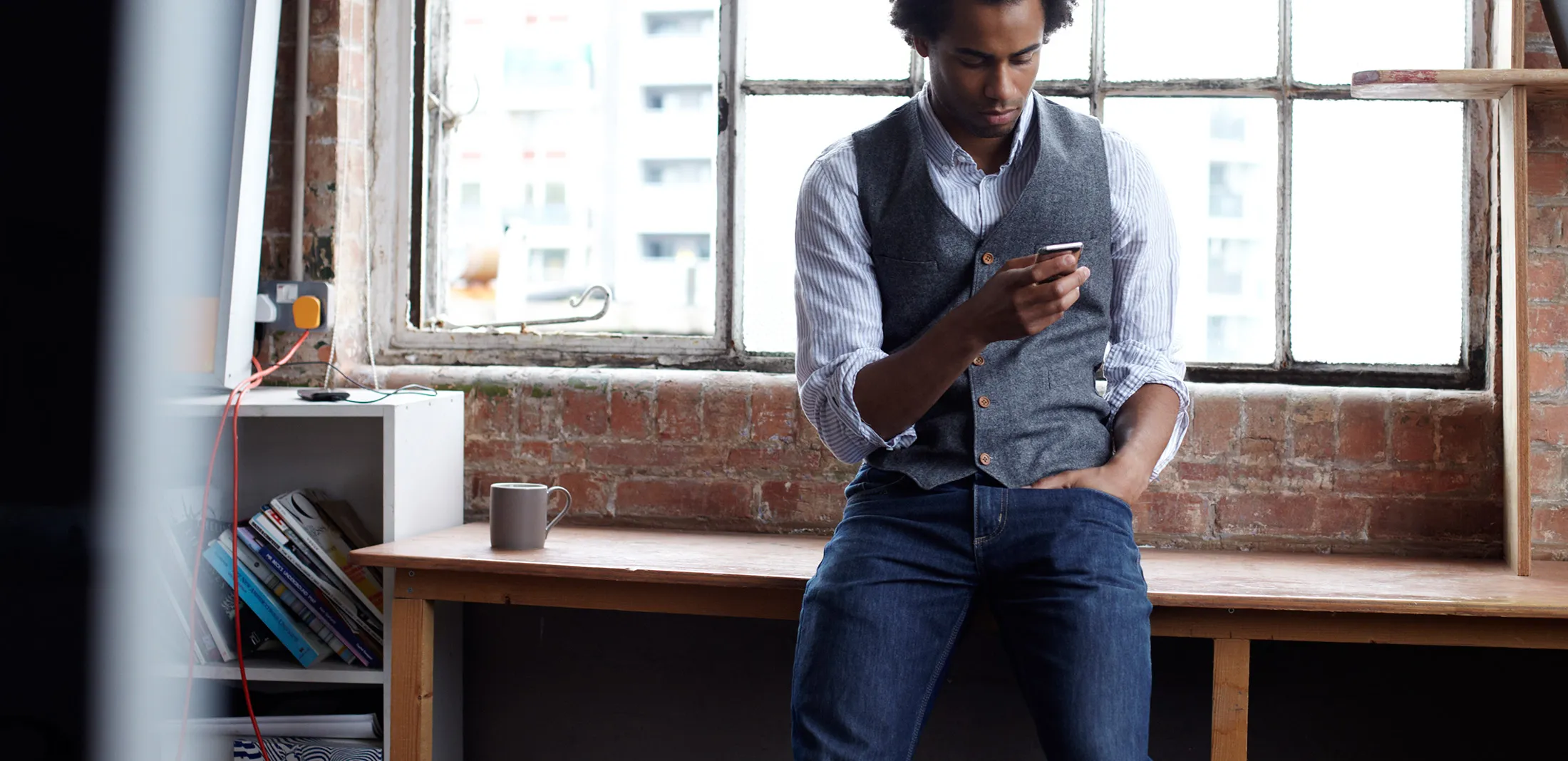 Young guy sitting on desk using smart phone