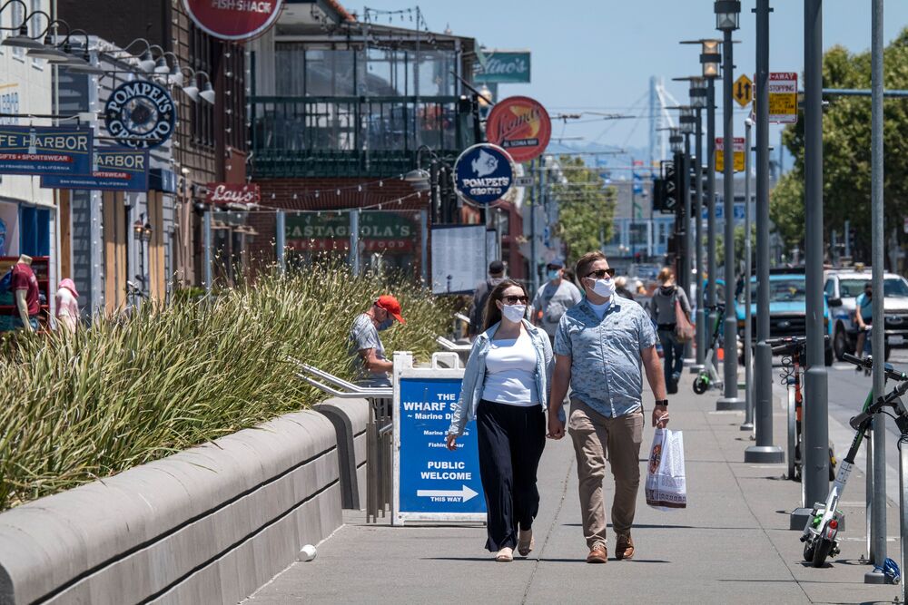 People wearing protective masks walk on Jefferson Street on Fisherman's Wharf in San Francisco, California, U.S.