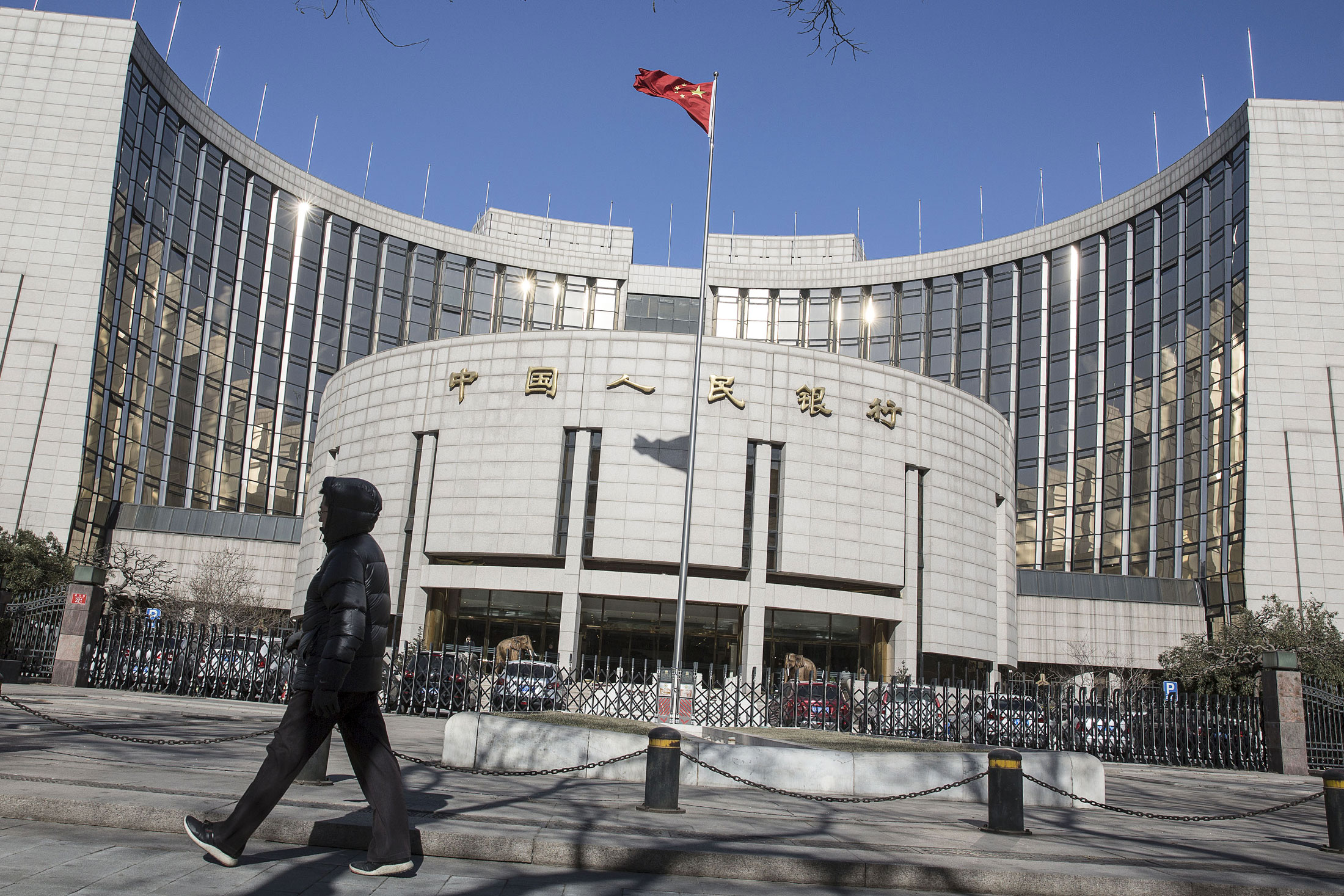 A pedestrian walks past the People's Bank of China (PBOC) headquarters in Beijing, China, on Monday, Jan. 18, 2016. China's economy slowed in December, capping the weakest quarter of growth since the 2009 global recession, as the Communist leadership struggles to manage a transition to consumer-led expansion.
