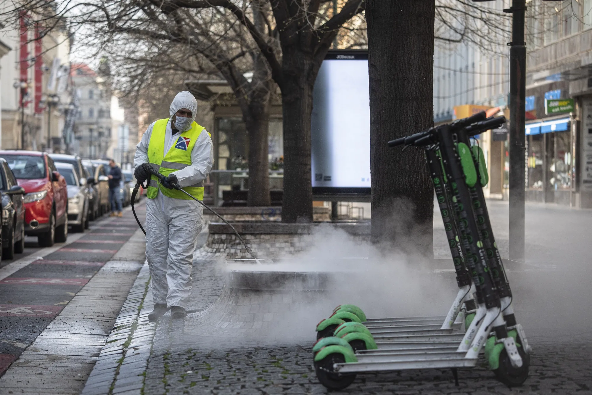 A municipal worker disinfects a street near electric rental scooters in Prague, Czech Republic, on March 18.