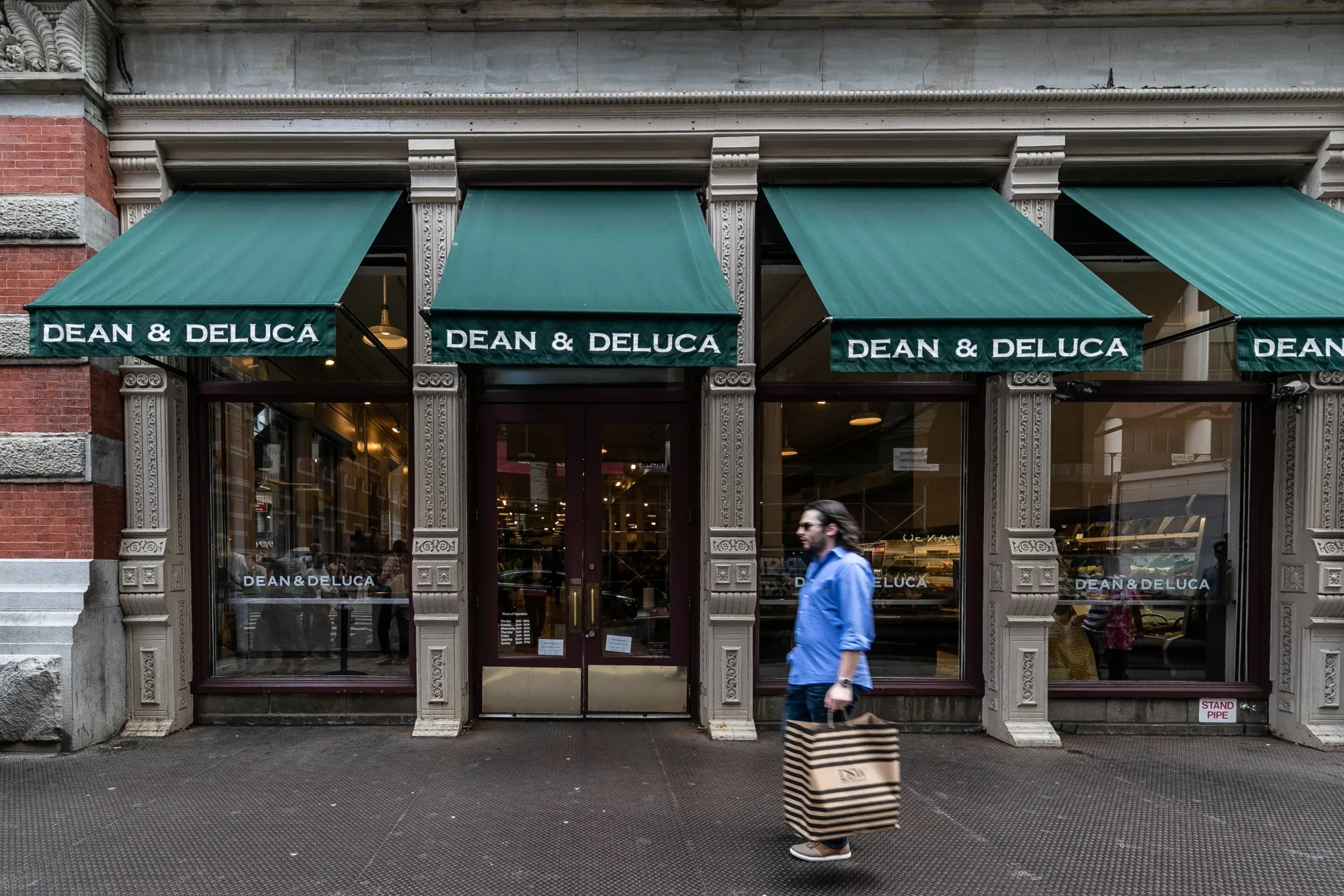 A pedestrian passes in front of a Dean &amp; DeLuca store in the Soho neighborhood of New York.