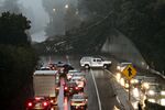 A large eucalyptus tree blocks the northbound lanes of Highway 13 just past Redwood Road in Oakland, Calif., Thursday, Dec. 23, 2021, as heavy rain falls across the region. Heavy overnight rains in Northern California left two people dead in a submerged car as authorities on Thursday urged residents of several Southern California mountain and canyon communities to voluntarily leave their homes because of possible mud and debris flows. (Jessica Christian/San Francisco Chronicle via AP)