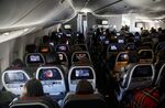 Passengers watch inflight entertainment (IFE) while sitting in economy class during an American Airlines Group Inc. Boeing 777-200 flight from Los Angeles International Airport (LAX) in Los Angeles, California, U.S., on Thursday, Oct. 1, 2020.