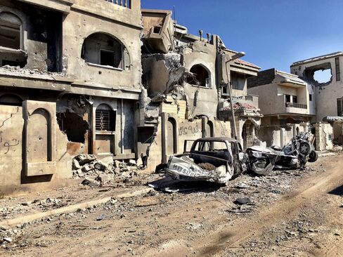 Destroyed buildings and vehicles line a street in Sirte.