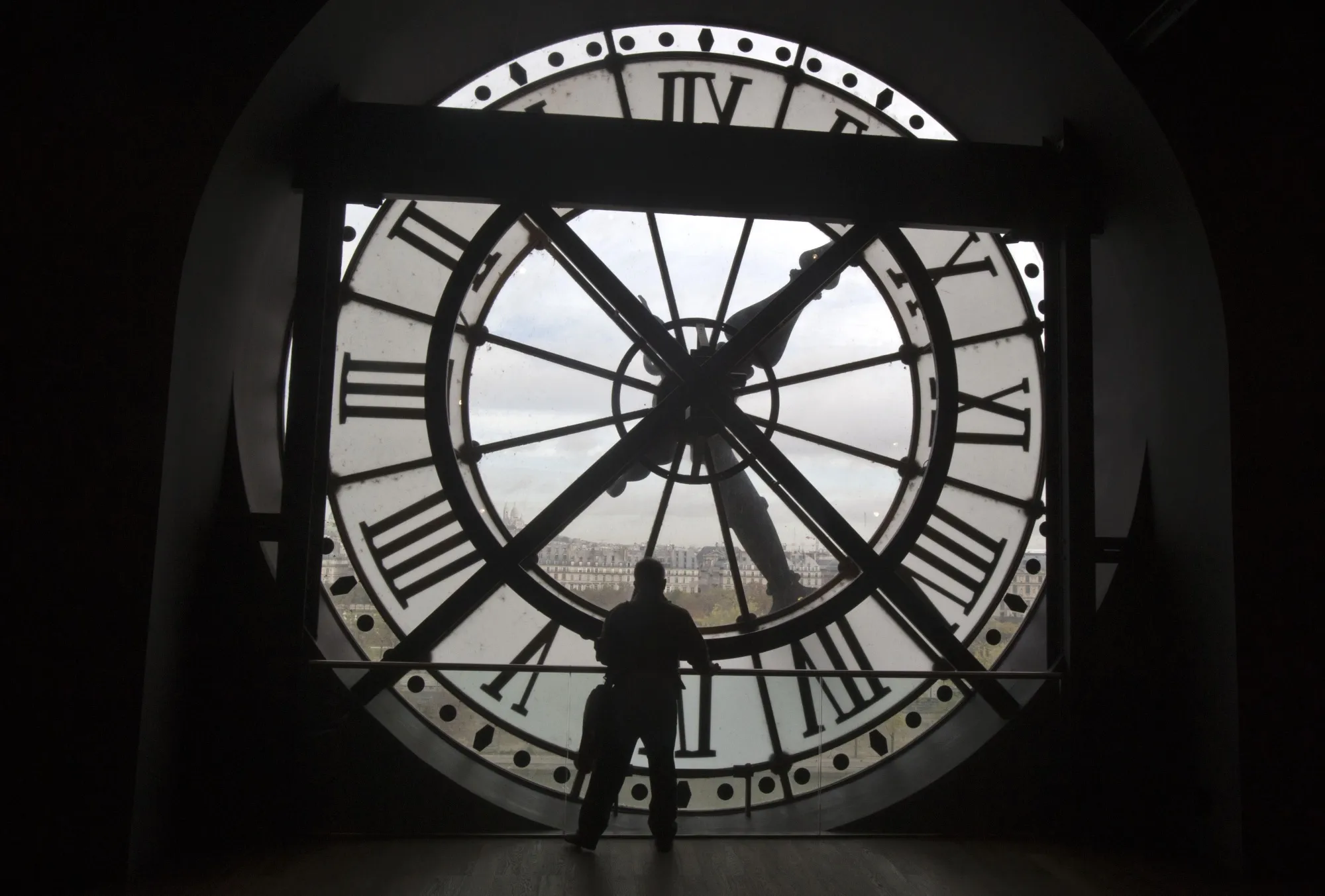 A visitor looks through the clock of the Orsay museum, overlooking Paris, Oct. 16, 2014. Short-term rental giant Airbnb is listing 11 iconic locations, including the Orsay, for a limited time in a splashy new marketing campaign. (AP Photo/Michel Euler, File)