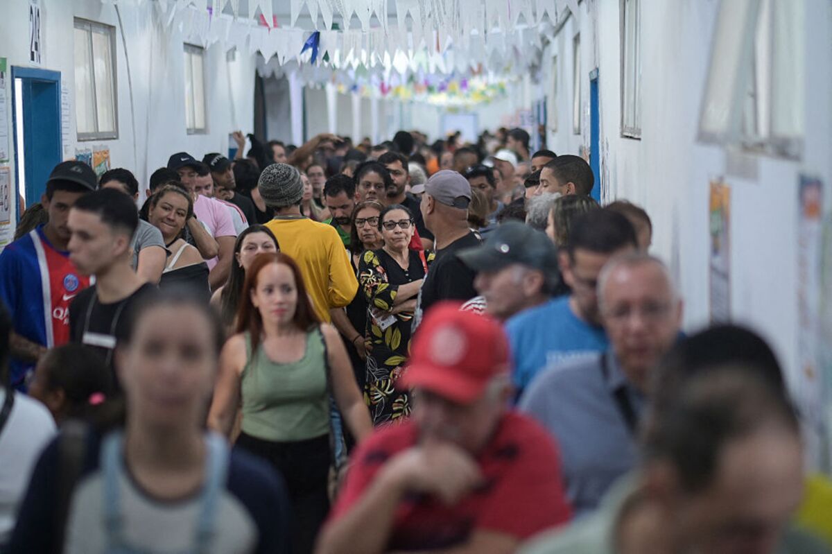Cédula anônima em urna diante de dois caminhos que representam diferentes reações dos mercados.