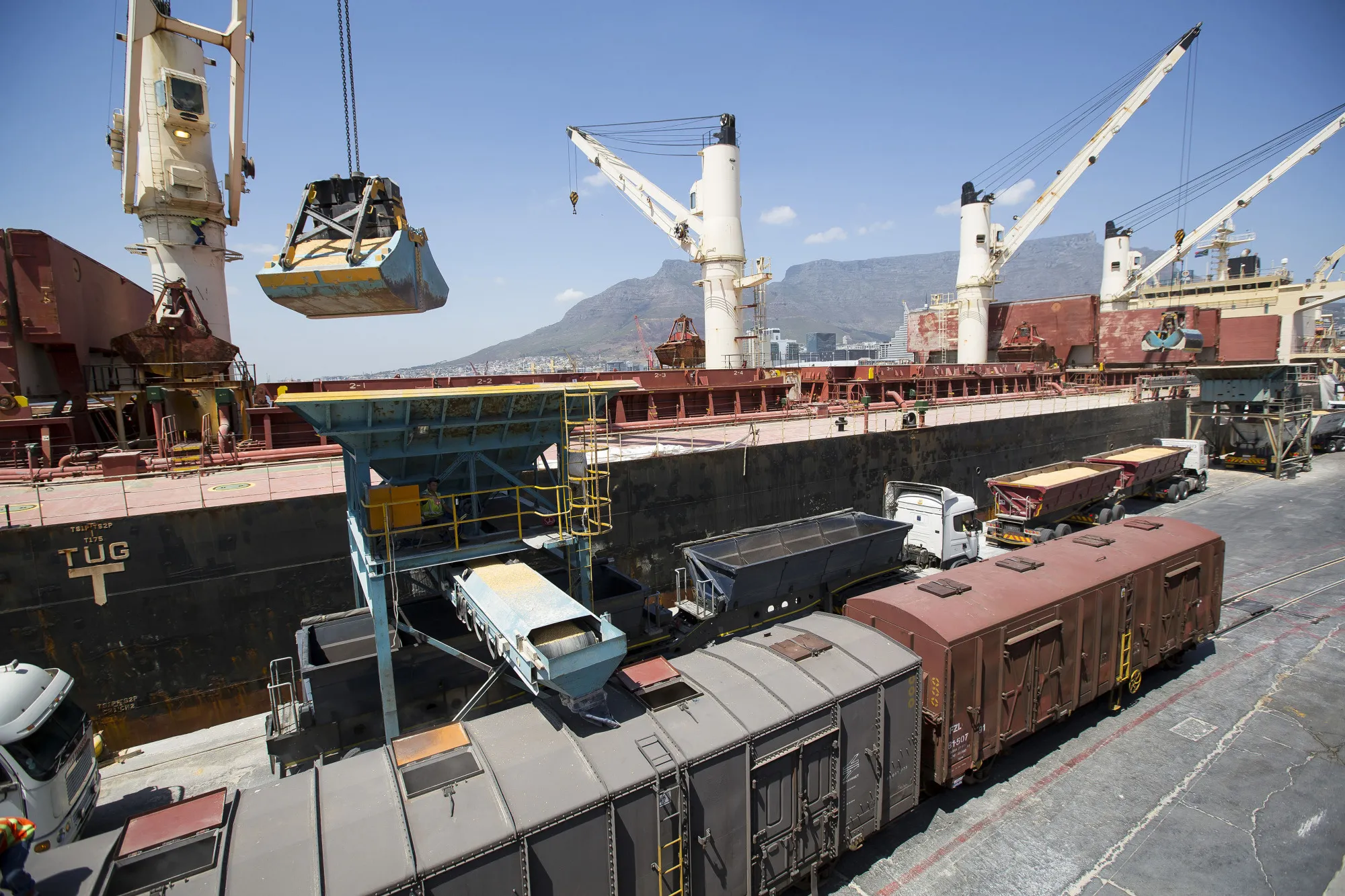 Road and rail transport wagons wait to load up with imported corn maize from a cargo vessel at the city port in Cape Town, South Africa