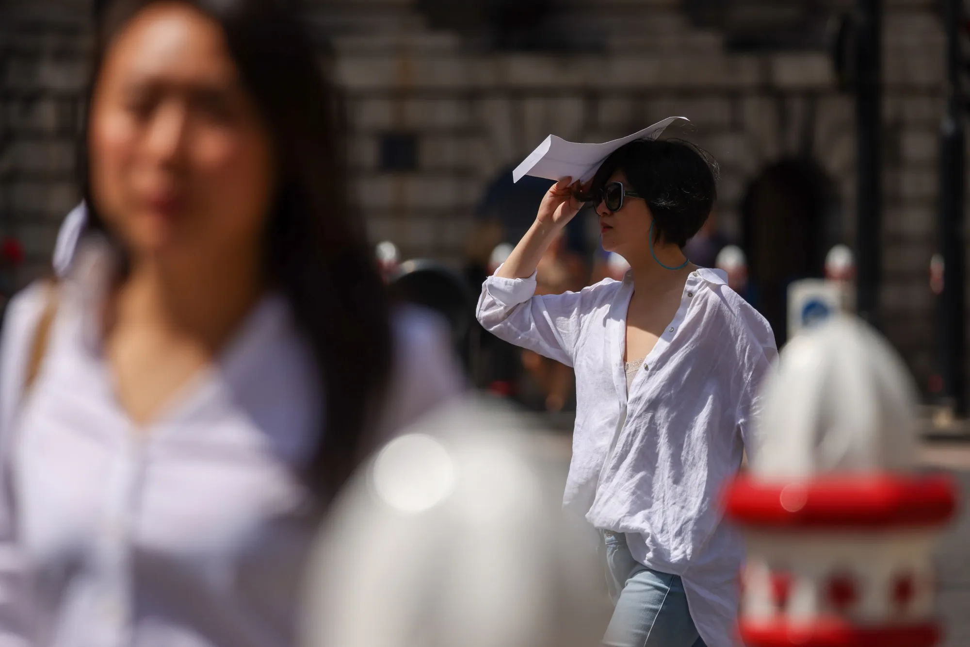 A pedestrian shades herself from the sun, in the City of London.