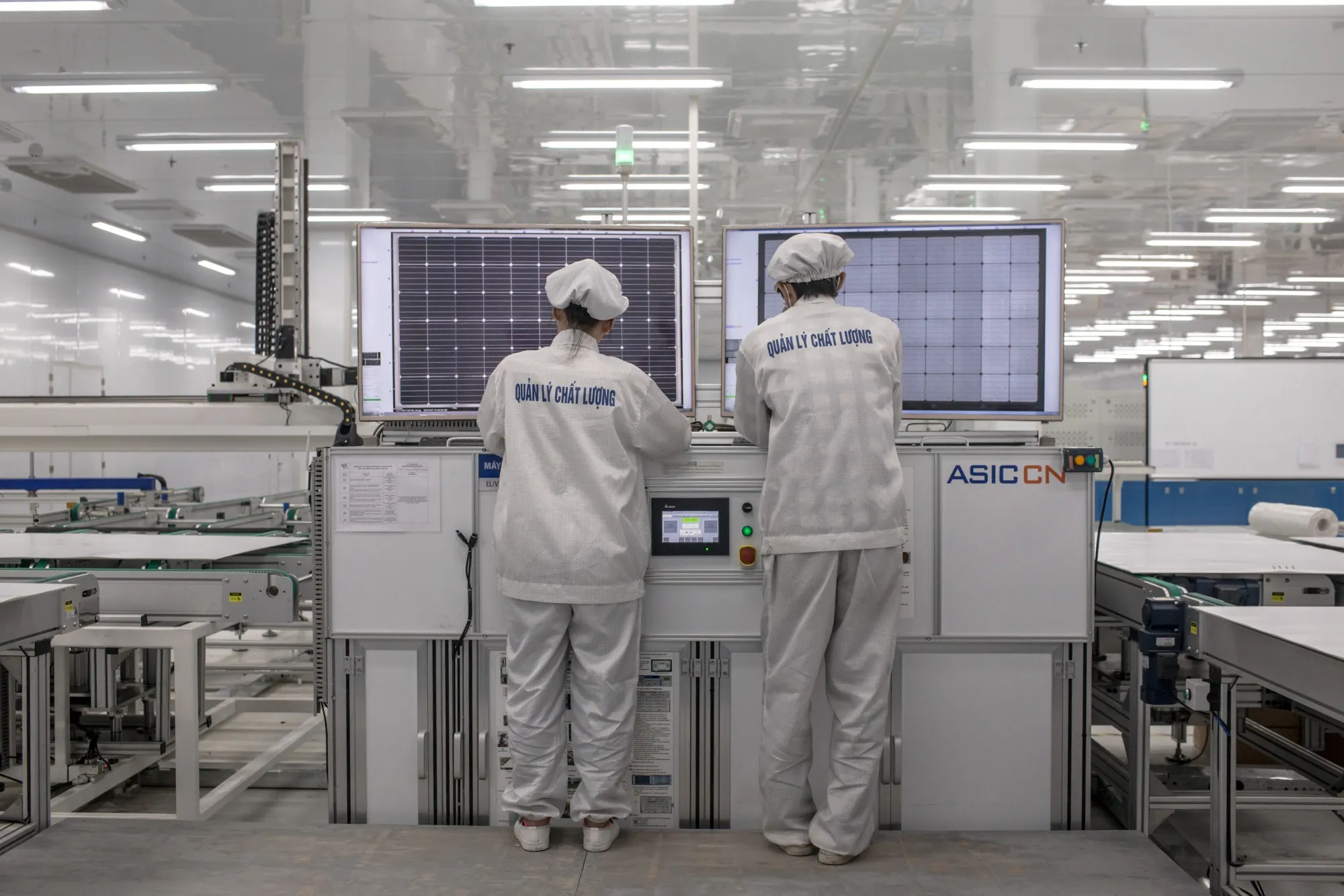 Workers inspect solar panels on a testing machine at a&nbsp;manufacturing facility in Vung Tau, Vietnam.