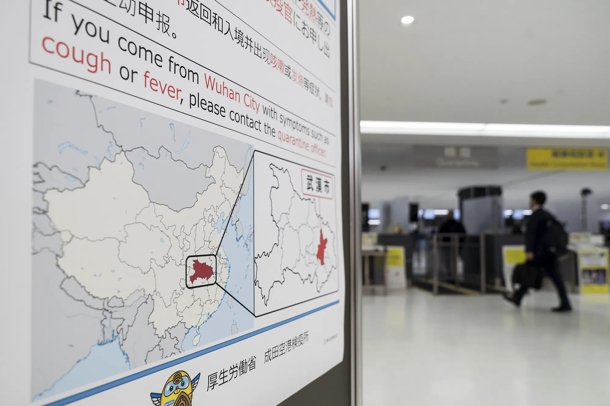 A passenger walks past a notice displayed near a quarantine station at Narita airport in Japan on Jan. 17.