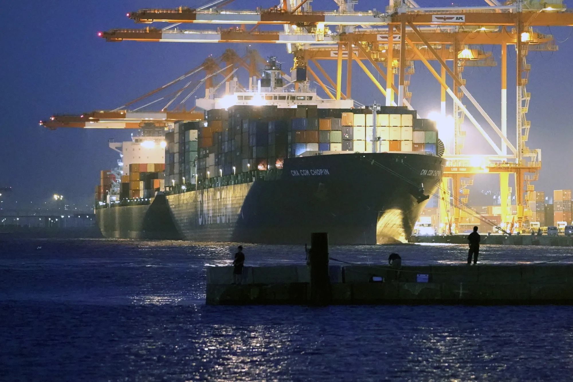 People fish&nbsp;as a container ship sits moored at a shipping terminal&nbsp;in Yokohama, Japan.