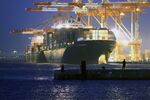 People fish as a container ship sits moored at a shipping terminal in Yokohama, Japan.