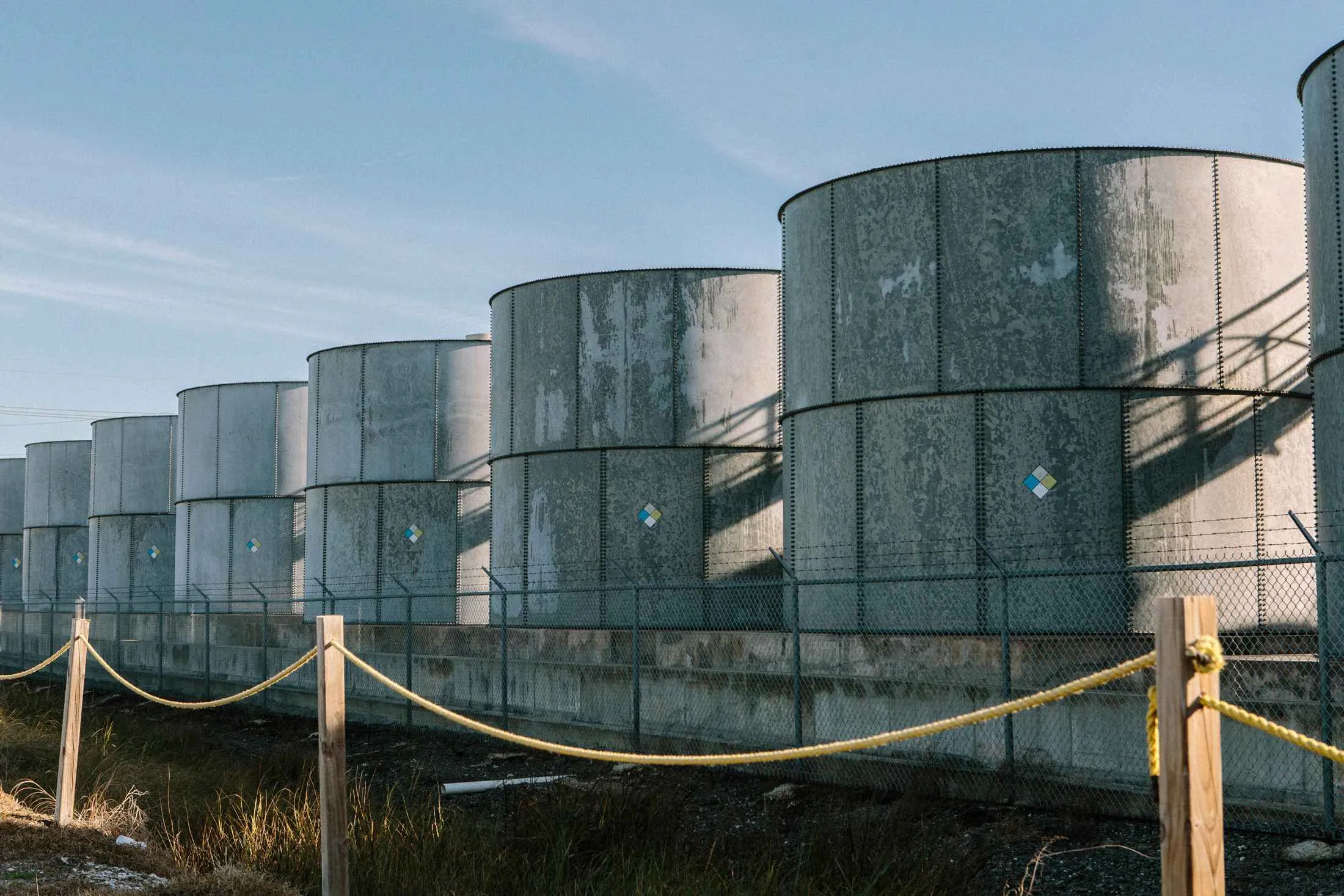 Oil storage tanks loom behind a barbed wire fence at Louisiana’s Port Fourchon.
