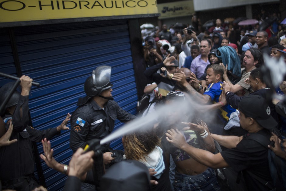 A woman is pepper sprayed as residents of Pavao-Pavaozinho slum clash with riot police during a protest against the death of Douglas Rafael da Silva Pereira after his burial in Rio de Janeiro, Brazil, Thursday, April 24, 2014.