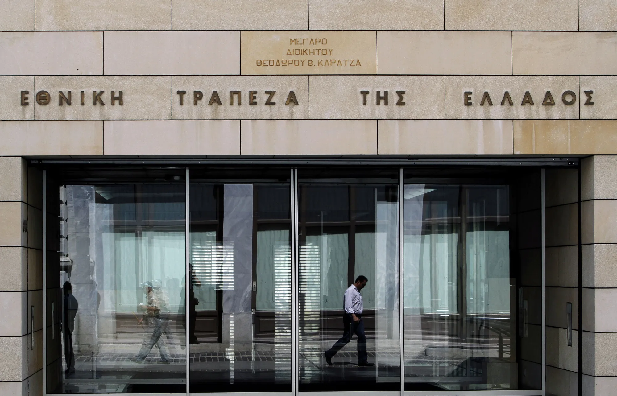 A man is reflected on the door of the headquarters of Greece's National Bank in Athens, Greece, on Wednesday, May 26, 2010.
