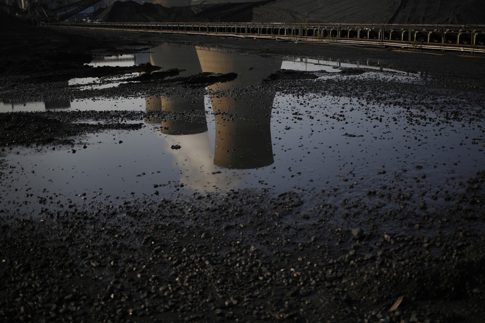 Cooling towers are reflected in a puddle at a coal-fired power plant&nbsp;in West Virginia.