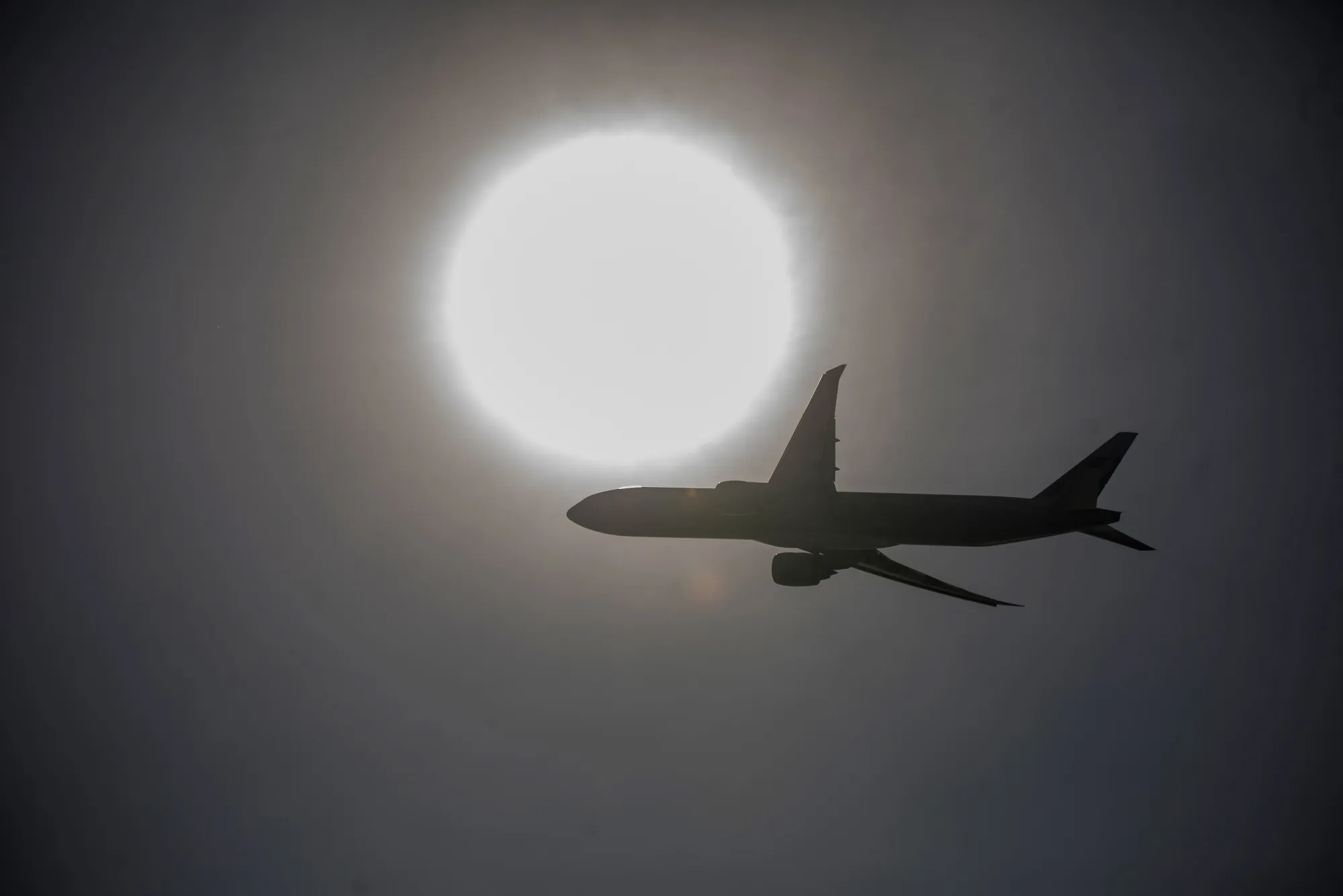 An aircraft is silhouetted as it flies over the Hong Kong International Airport in Hong Kong.
