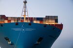 A crew member stands near shipping containers on the prow of the Maersk Mc-Kinney Moller Triple-E Class container ship, operated by A.P. Moeller-Maersk A/S, as it arrives at the port of Aarhus.
