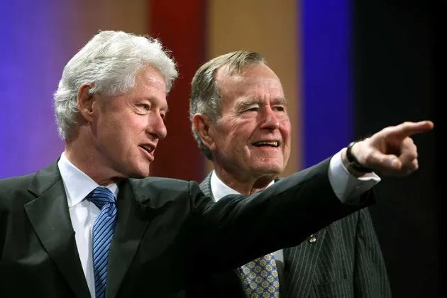 Bill Clinton stands with George H.W. Bush during the opening session of the Clinton Global Initiative on Sept. 24, 2008, in New York