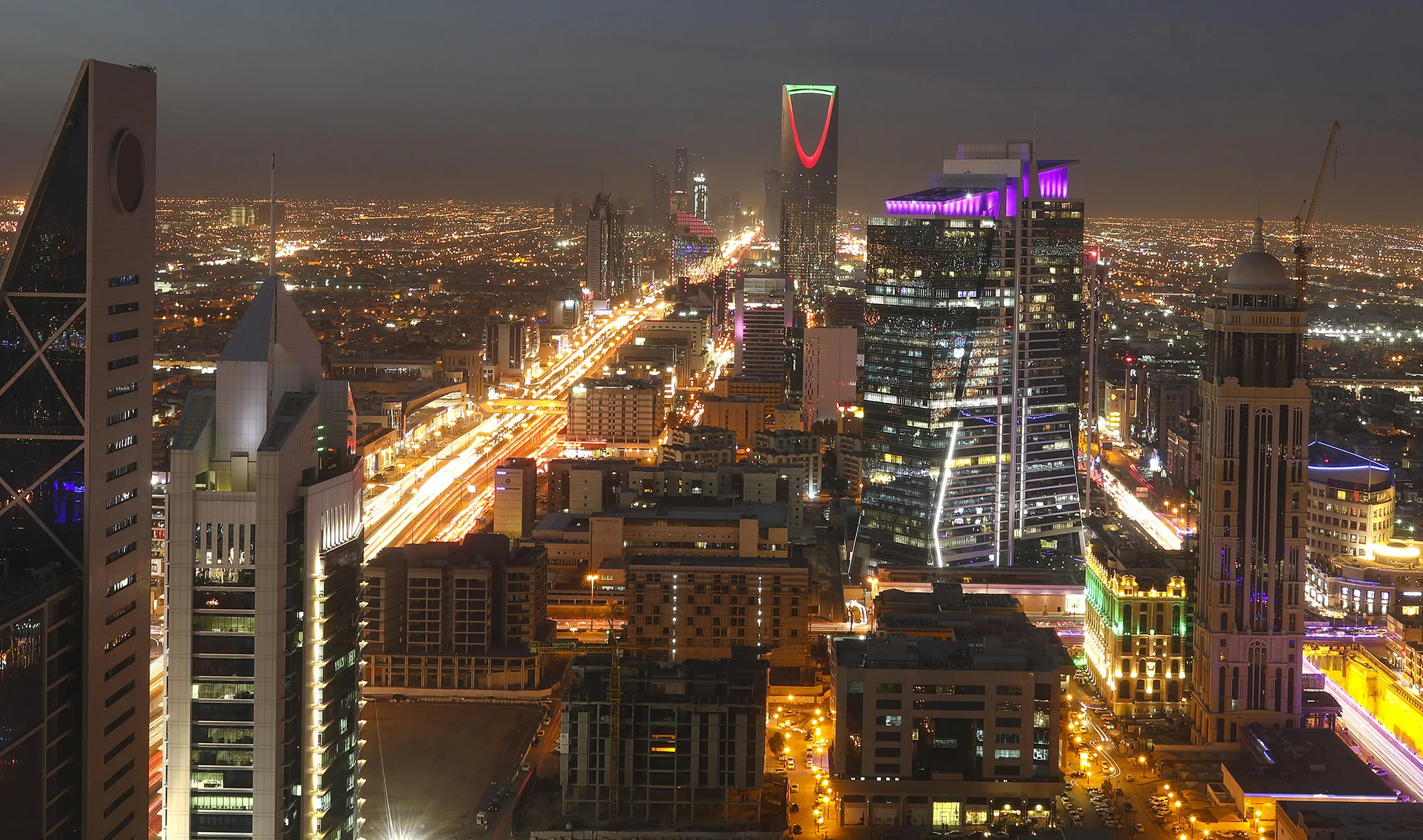 Light trails from automobile traffic traveling along the King Fahd highway, left, and Olaya Street, right, lead towards the Kingdom Tower, center rear, in Riyadh, Saudi Arabia.
