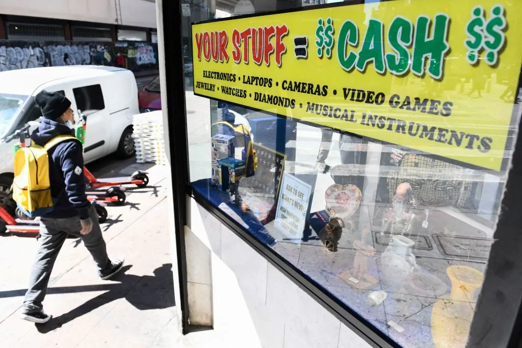 A pedestrian walks past a pawn shop in downtown Los Angeles. Pawn shop loans are on the rise as US consumer sentiment dives.