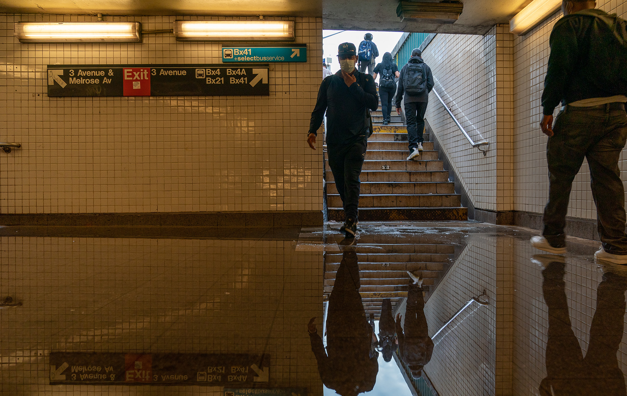 Commuters walk into a flooded 3rd Avenue/149th st subway station in New York.