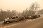 A pickup truck and a trailer that burned overnight in the middle of state Highway 96 are seen destroyed by the McKinney Fire in the community of Klamath River, Calif., Saturday, July 30, 2022. (Scott Stoddard/Grants Pass Daily Courier via AP)