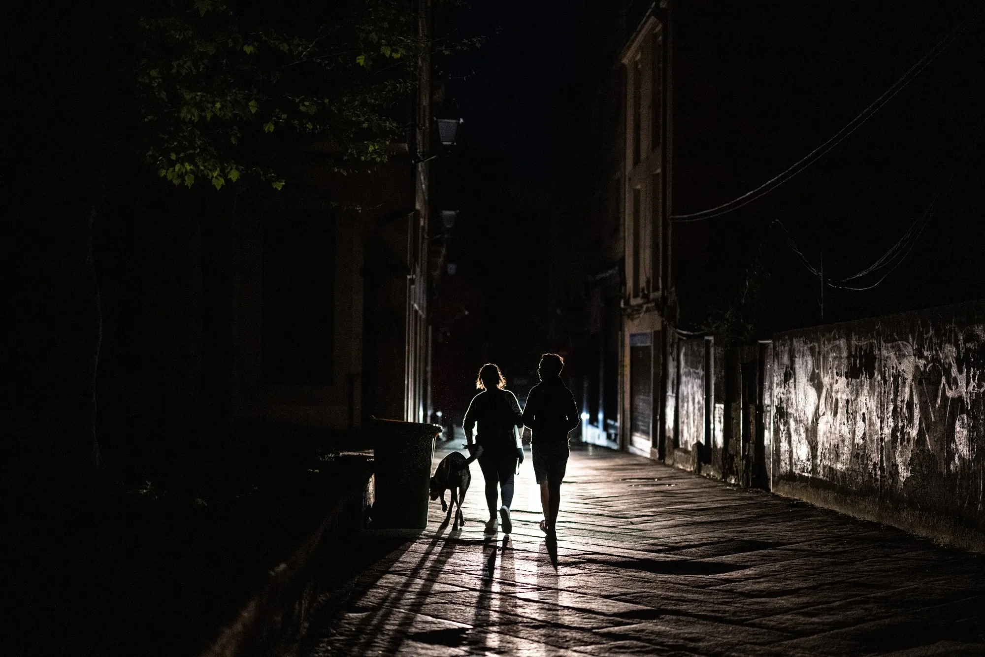 Pedestrians walk on an unlit street during a power outage in Ourense, Spain, on Monday, April 28, 2025. Spain and Portugal lost power shortly after 12:30 p.m. local time in a massive blackout that idled public transport, airports and phone services, bringing the daily activities of millions to a halt.