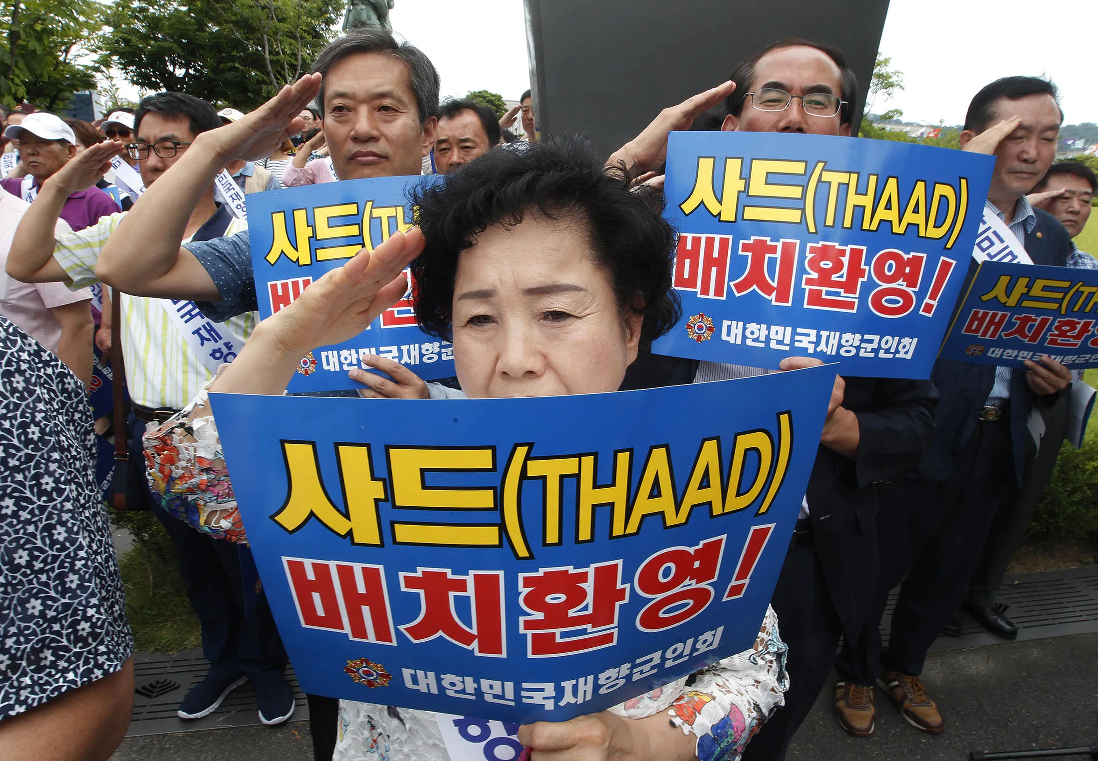 Members of Korean Veterans Association salute during a rally to support a deployment of the Terminal High-Altitude Area Defense, or THAAD, in front of the Defense Ministry in Seoul, South Korea, Friday, July 15, 2016. An advanced U.S. missile defense system will be deployed in a rural farming town in southeastern South Korea, Seoul officials announced Wednesday, angering not only North Korea and China but also local residents who fear potential health hazards that they believe the U.S. system might cause. The signs read ' Support a deployment of the THAAD.'
