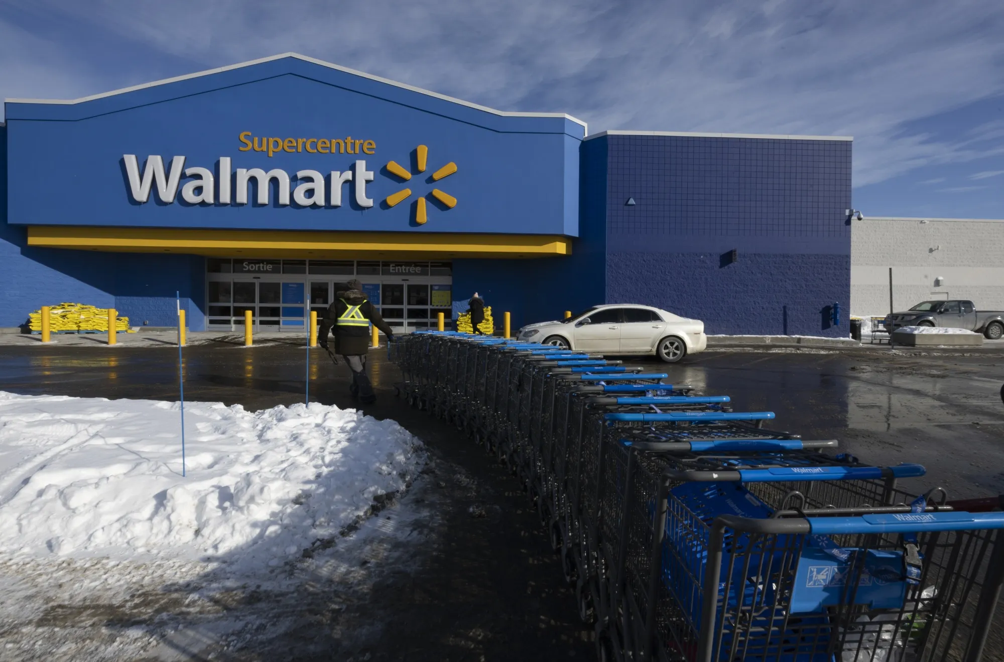 A worker pulls shopping carts outside a Walmart store in Montreal, Quebec.