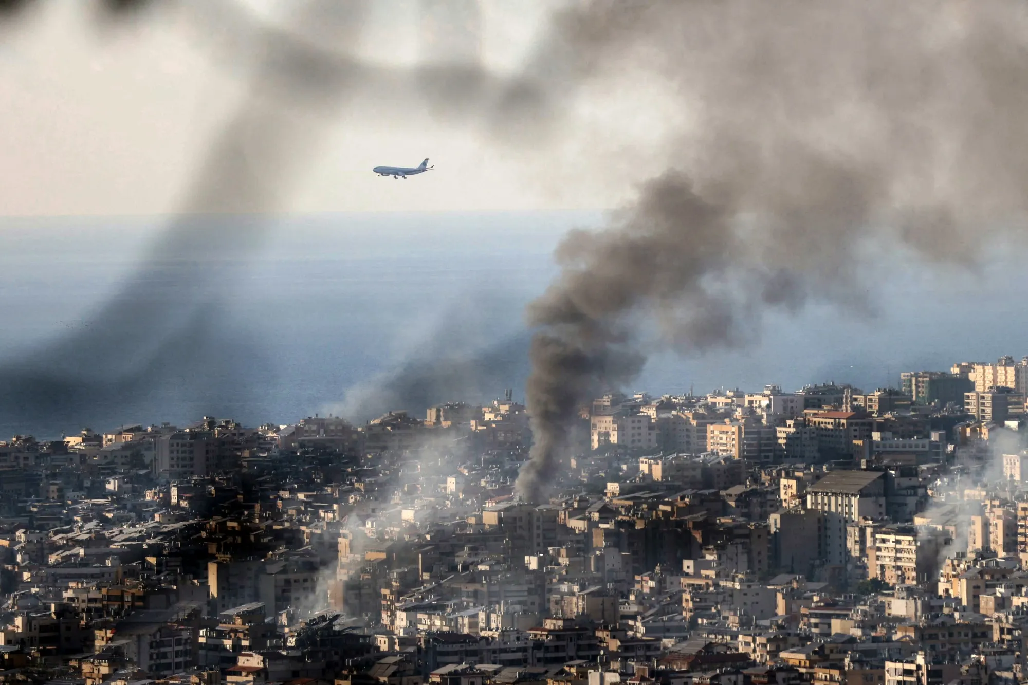 A commercial aircraft approaches the runway of the nearby Beirut airport as smoke rises from an Israeli airstrike in 2024.