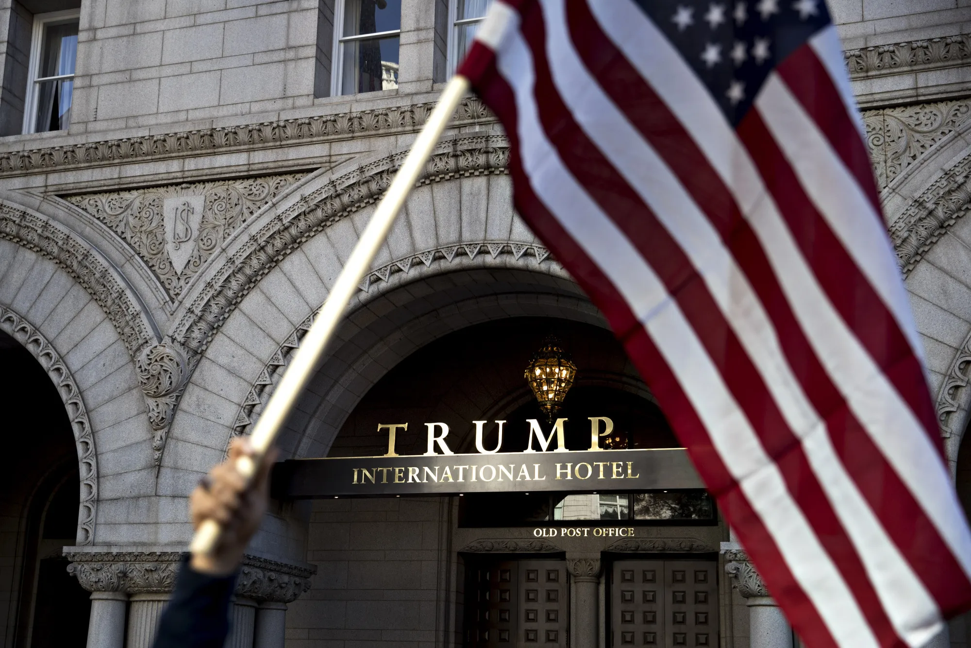A demonstrator holds an American flag near the Trump International Hotel during a protest in Washington on Oct. 18, 2017.
