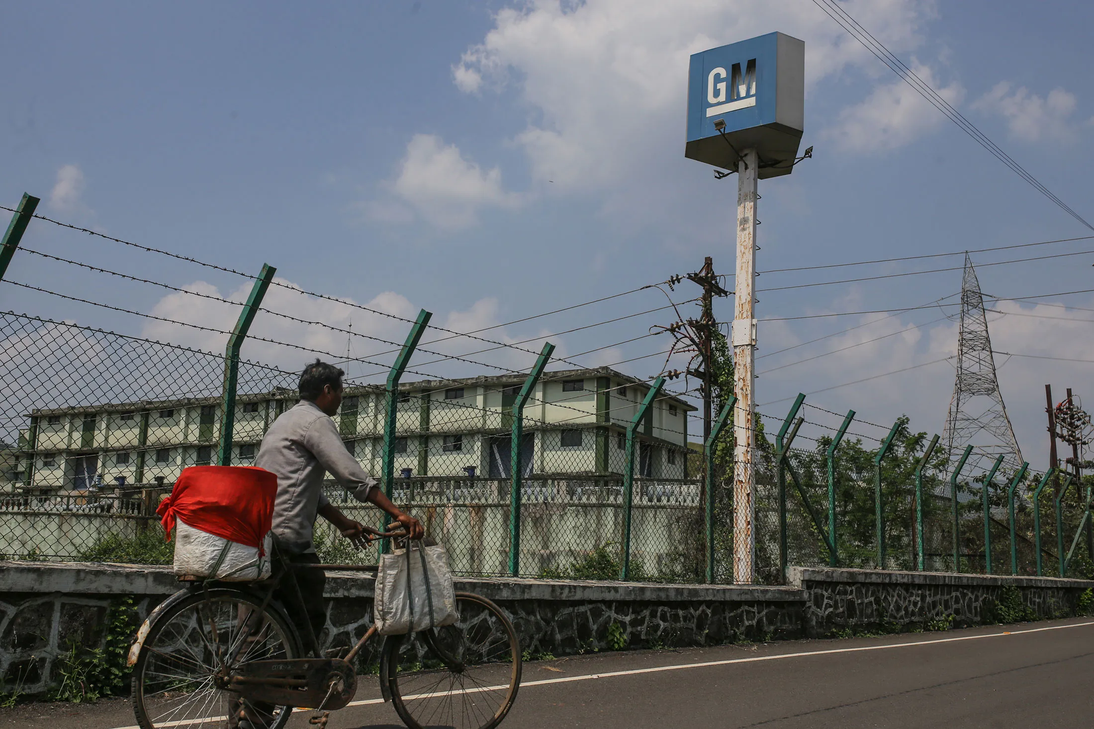 A cyclist passes General Motors’&nbsp;shuttered manufacturing plant in Talegaon, India.