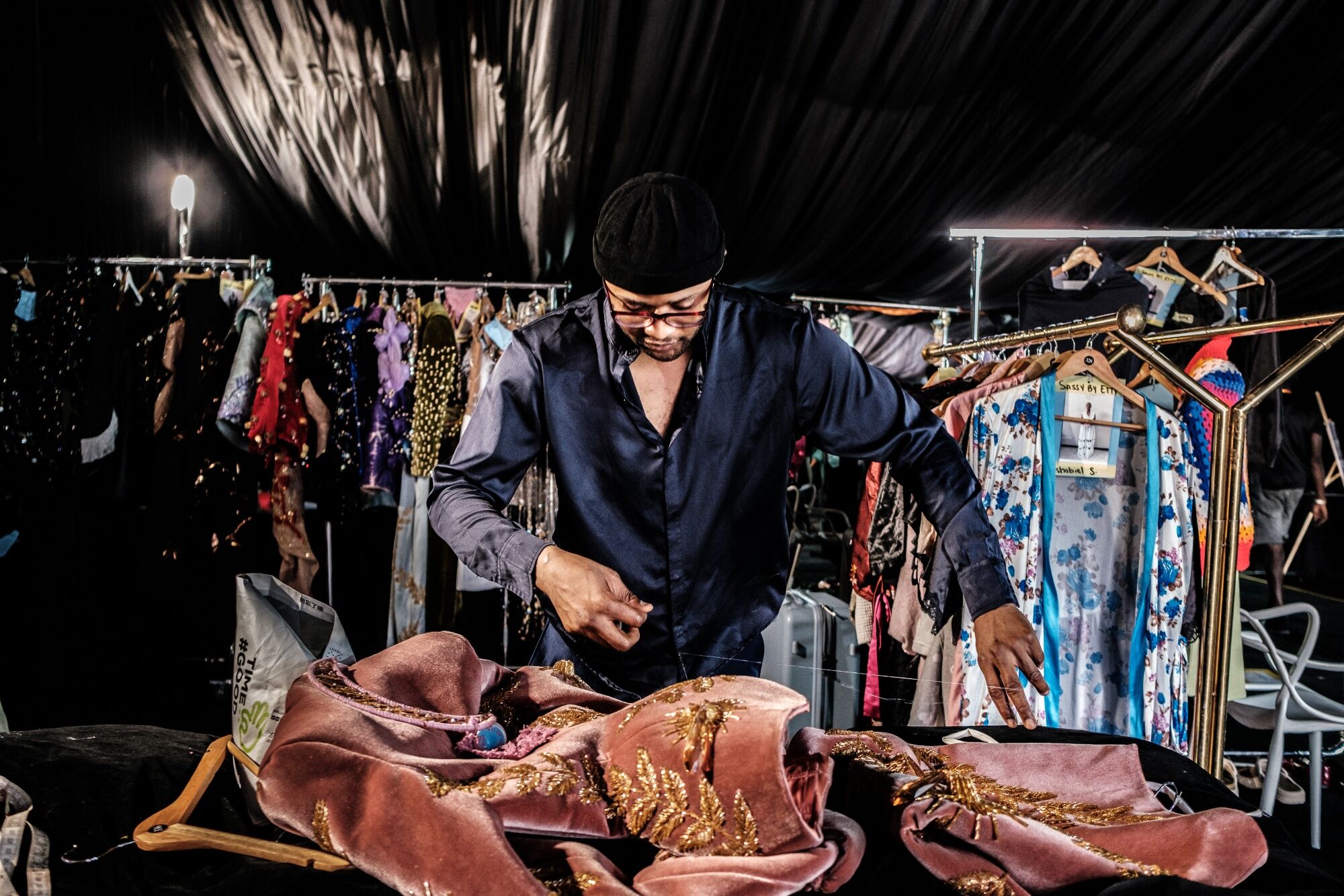 Fashion designer Sevon Dejana sewing a dress backstage before his Lagos fashion show.