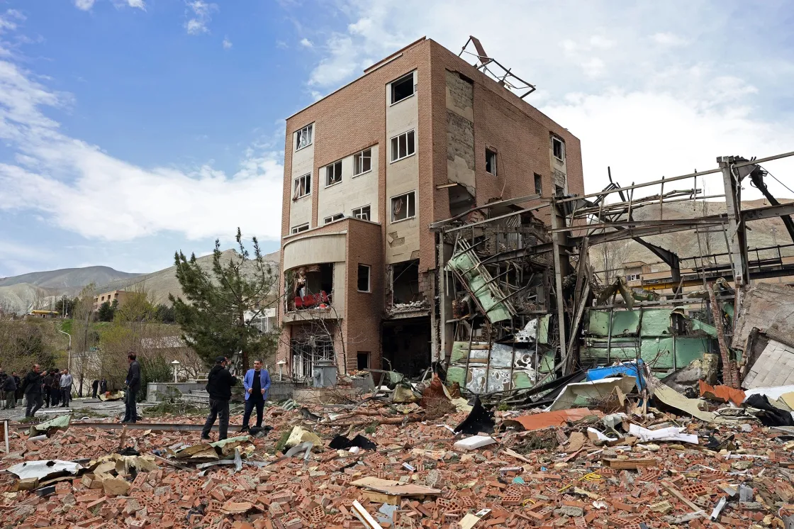 People gather around a damaged building following an airstrike&nbsp;in Tehran.