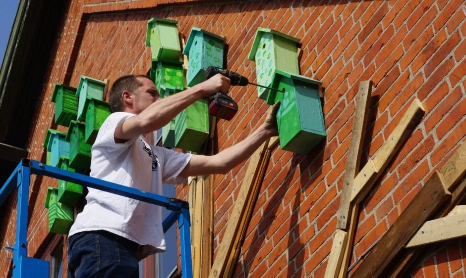 Artist Thomas Dambo at work on a birdhouse mural on a library in Hvalsø, outside of Copenhagen.