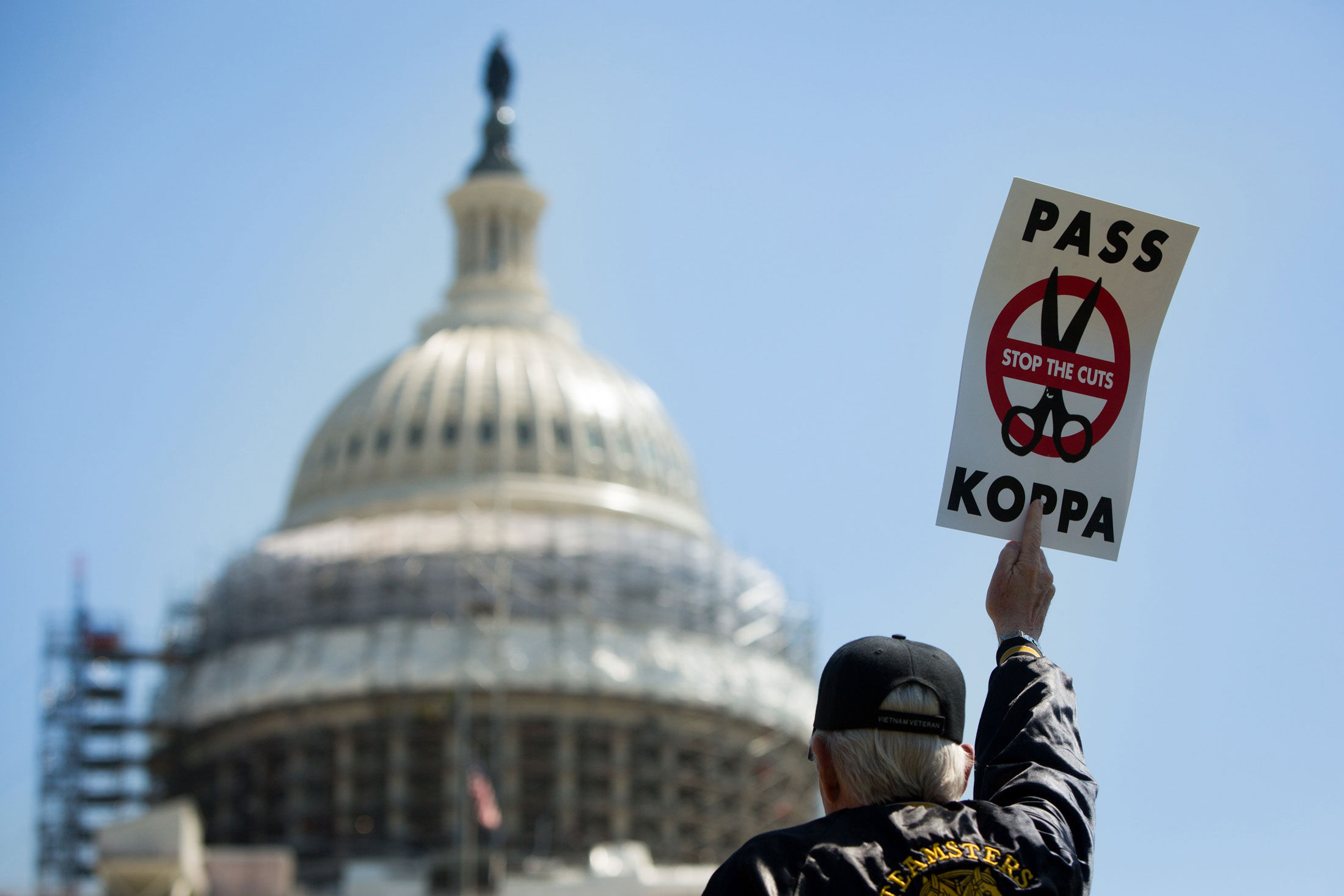 A demonstrator holds a sign at a rally to oppose cuts in pension benefits on April 14 in front of the U.S. Capitol building in Washington.
