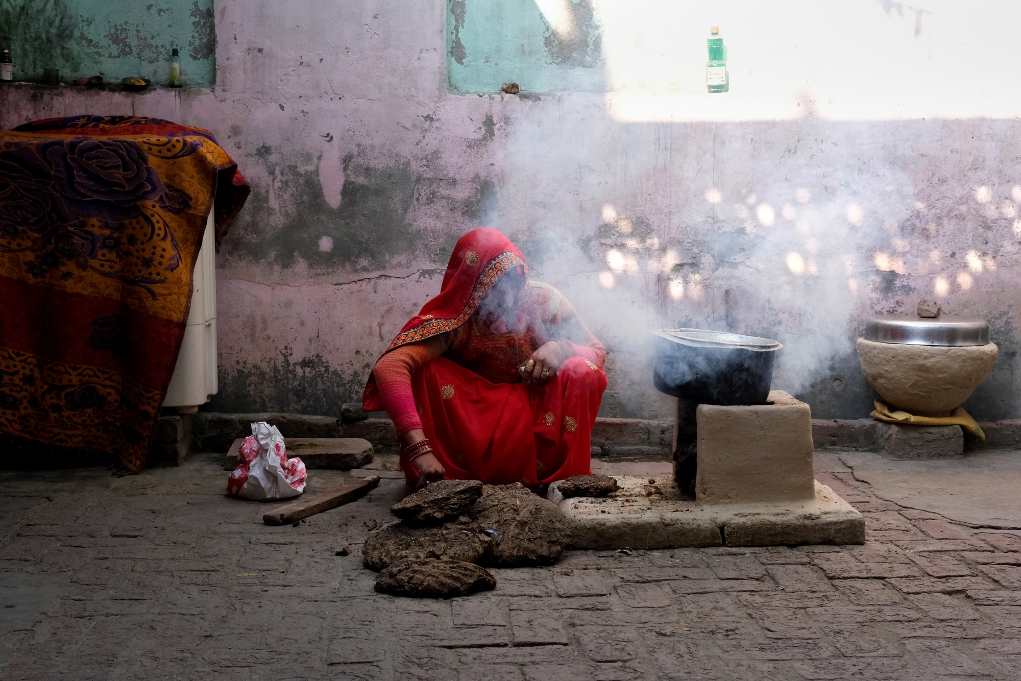 Une femme utilise du fumier pour cuisiner dans sa maison de village.