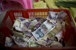 Chinese yuan banknotes sit in a container at a stall in Shenzhen, China.
