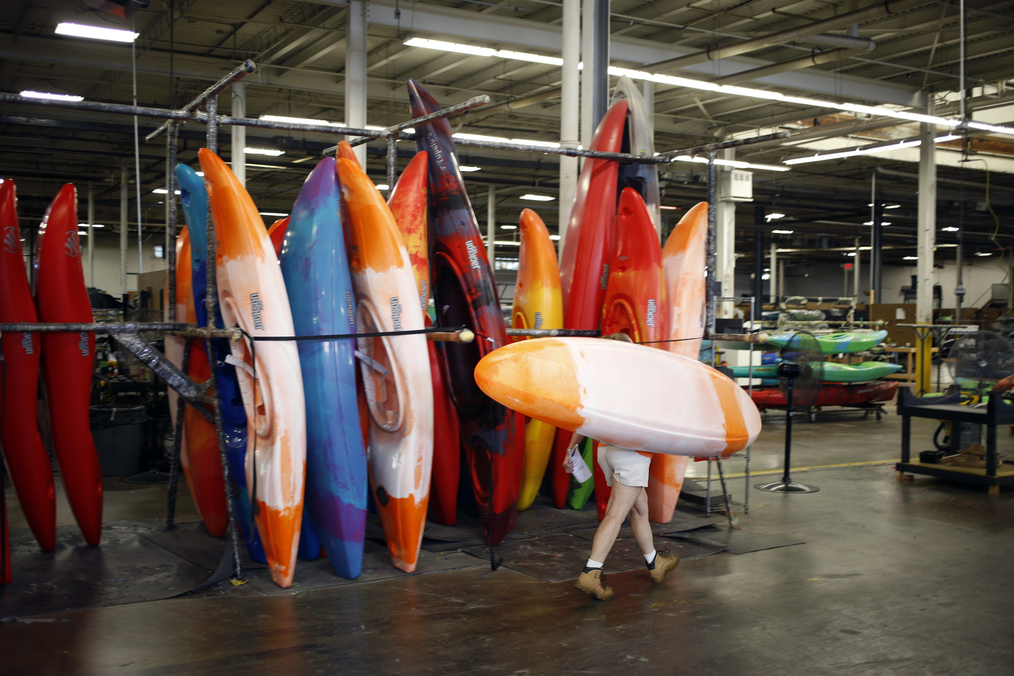 An employee carries a newly manufactured plastic kayak on the production floor at a&nbsp;factory in Sparta, Tennessee.
