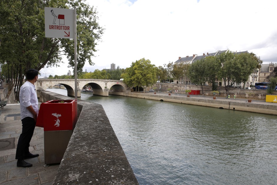 Voilà! A journalist demonstrates the proper use of a &quot;uritrottoir&quot; on the Ile Saint-Louis along the Seine.