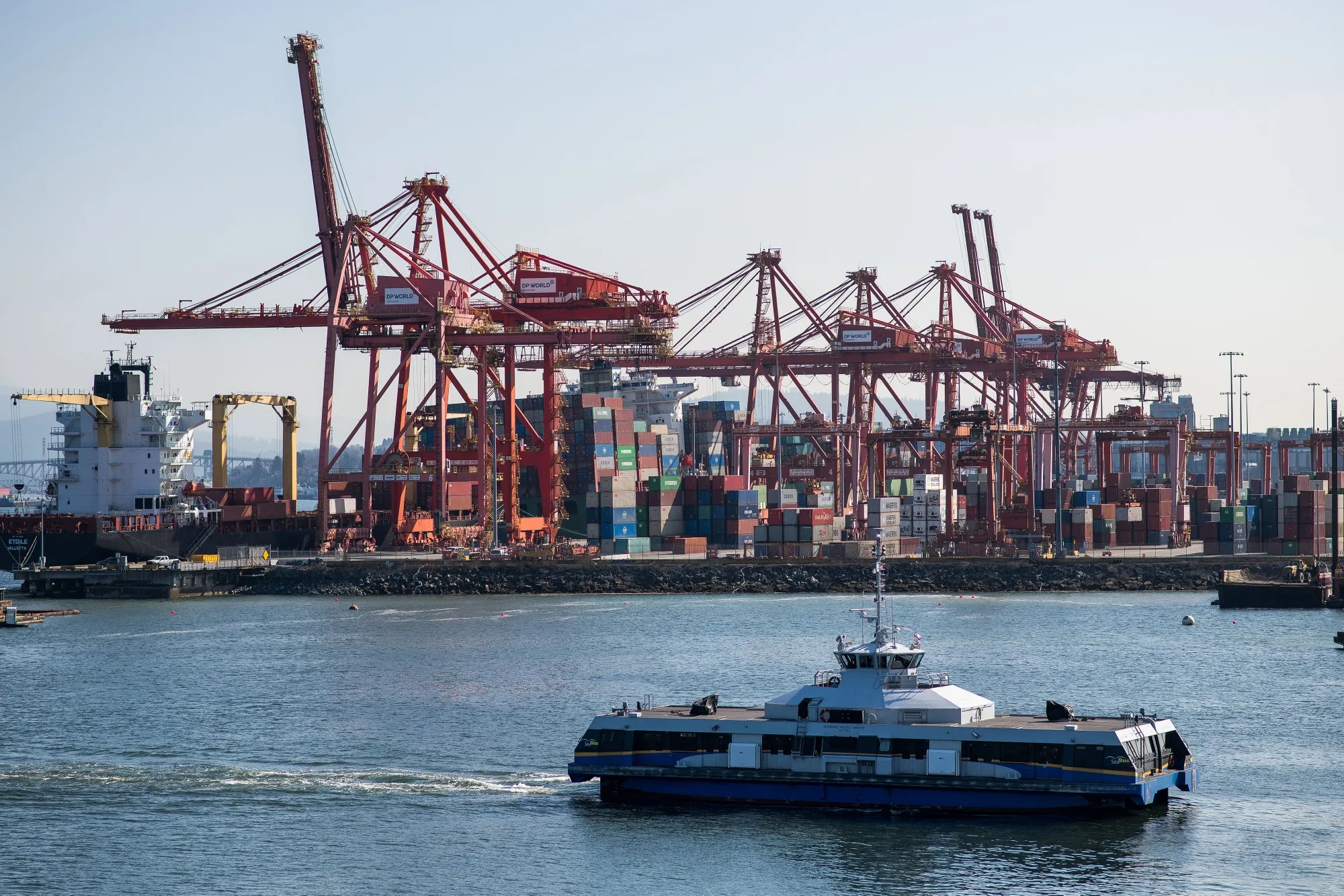 A boat sails past the DP World container terminal on Vancouver Harbour in Vancouver.