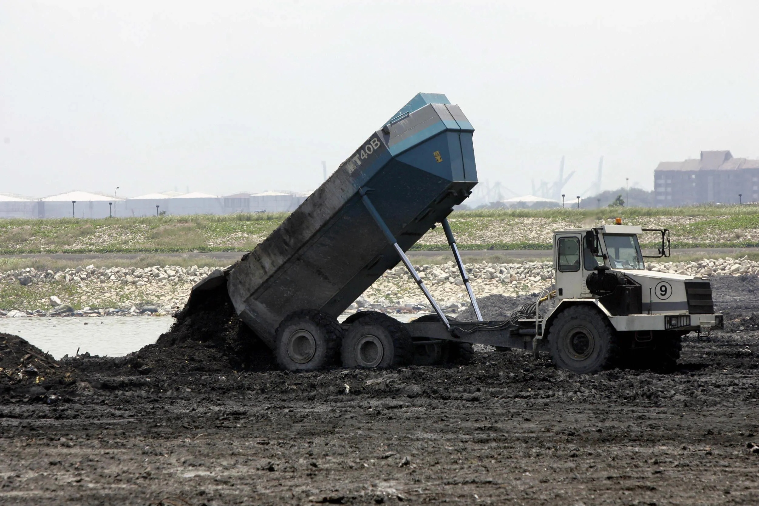 A dump truck spreads burned garbage at Singapore's Semakau island landfill.