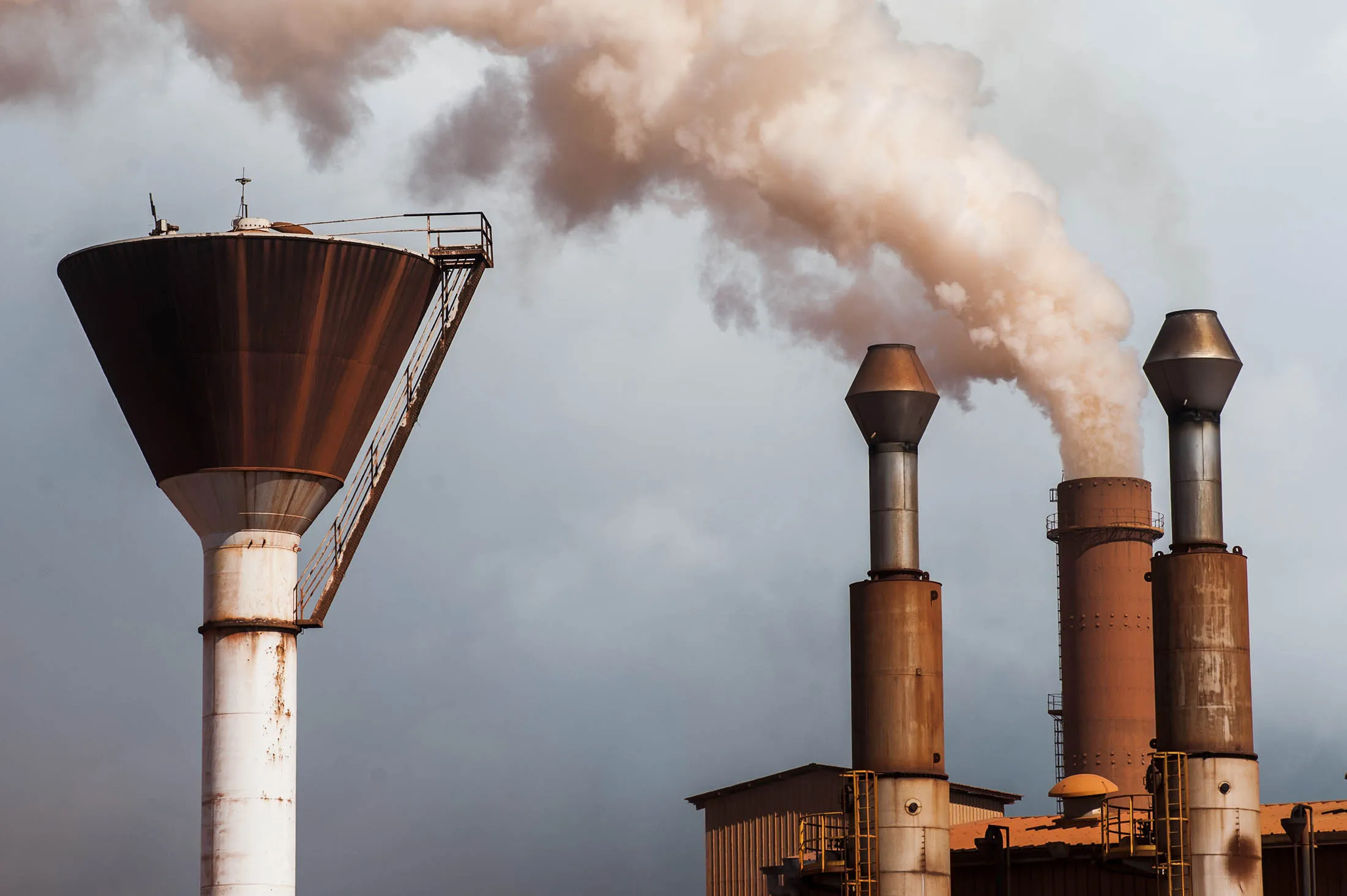 A chimney emits smoke at a bauxite treatment plant operated by Compagnie des Bauxites de Guinee (CBG) in Kamsar, Guinea, on Monday, Sept. 7, 2015. With 43 percent of its population of 12 million living on less than $1.25 a day, Guinea ranks amongst the most impoverished countries in the world, according to World Bank data.
